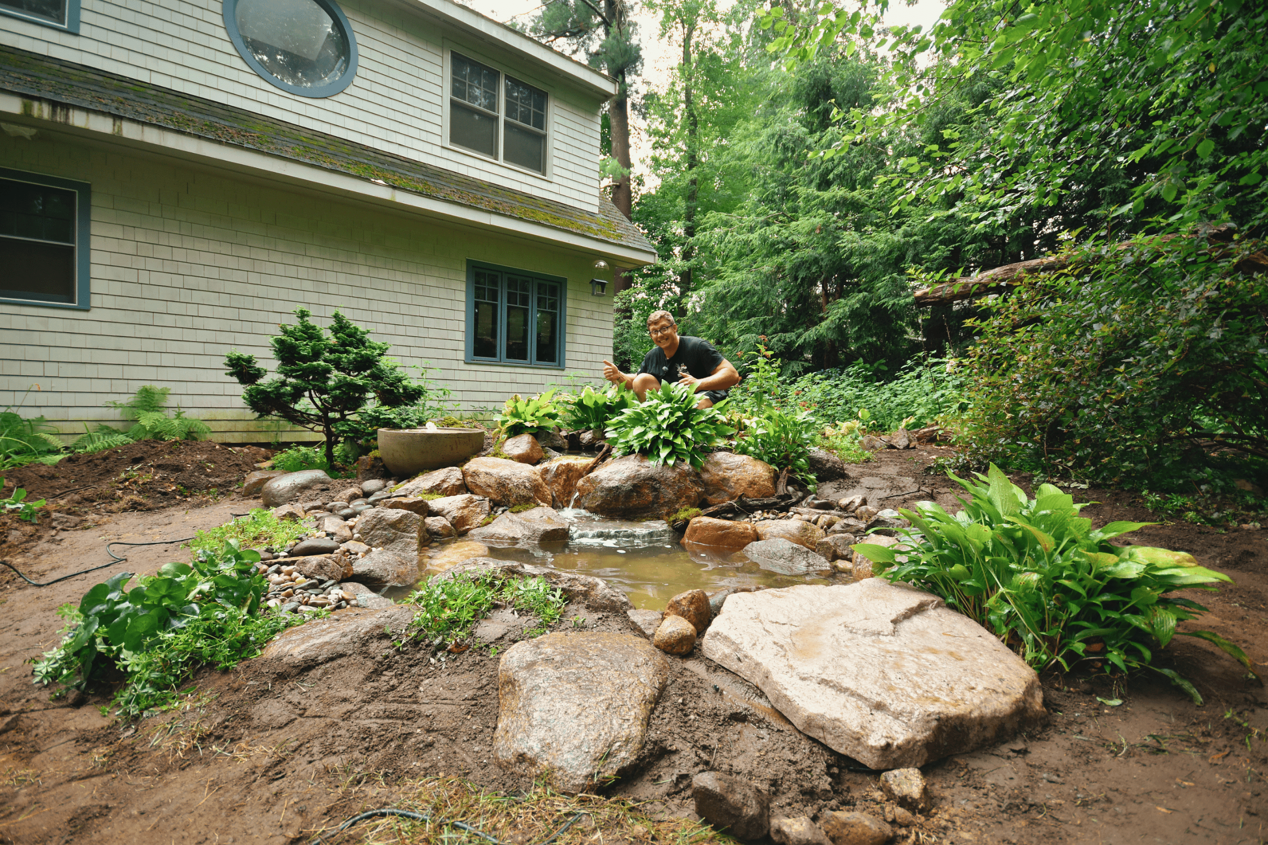 Man gardening by backyard pond with lush plants